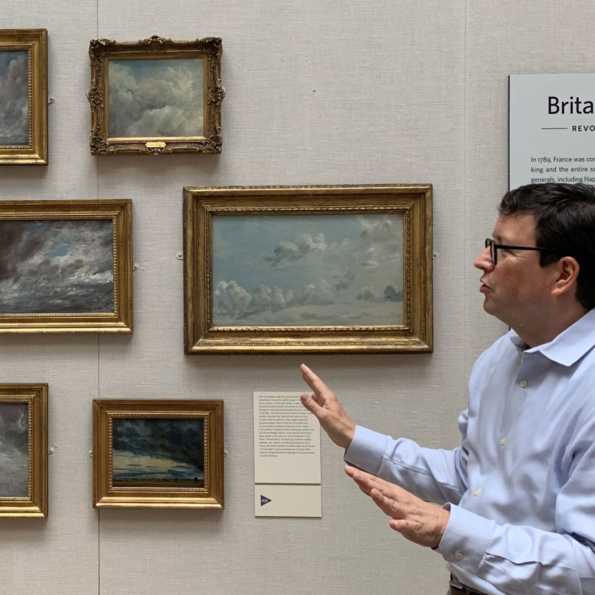 Man pointing to paintings of clouds