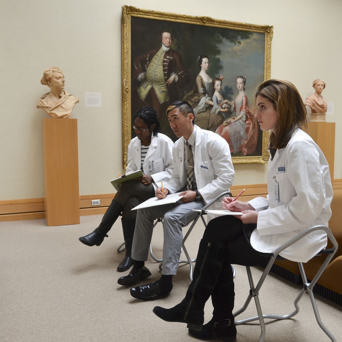 Three students drawing in a gallery